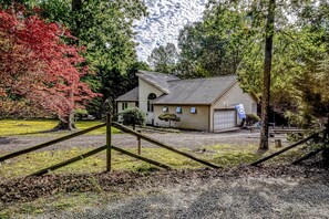 A house with a garage, surrounded by trees and a gravel driveway. - Dog-friendly Home With Free Wifi, Central AC, Firepit, & Furnished Deck (Mineral)