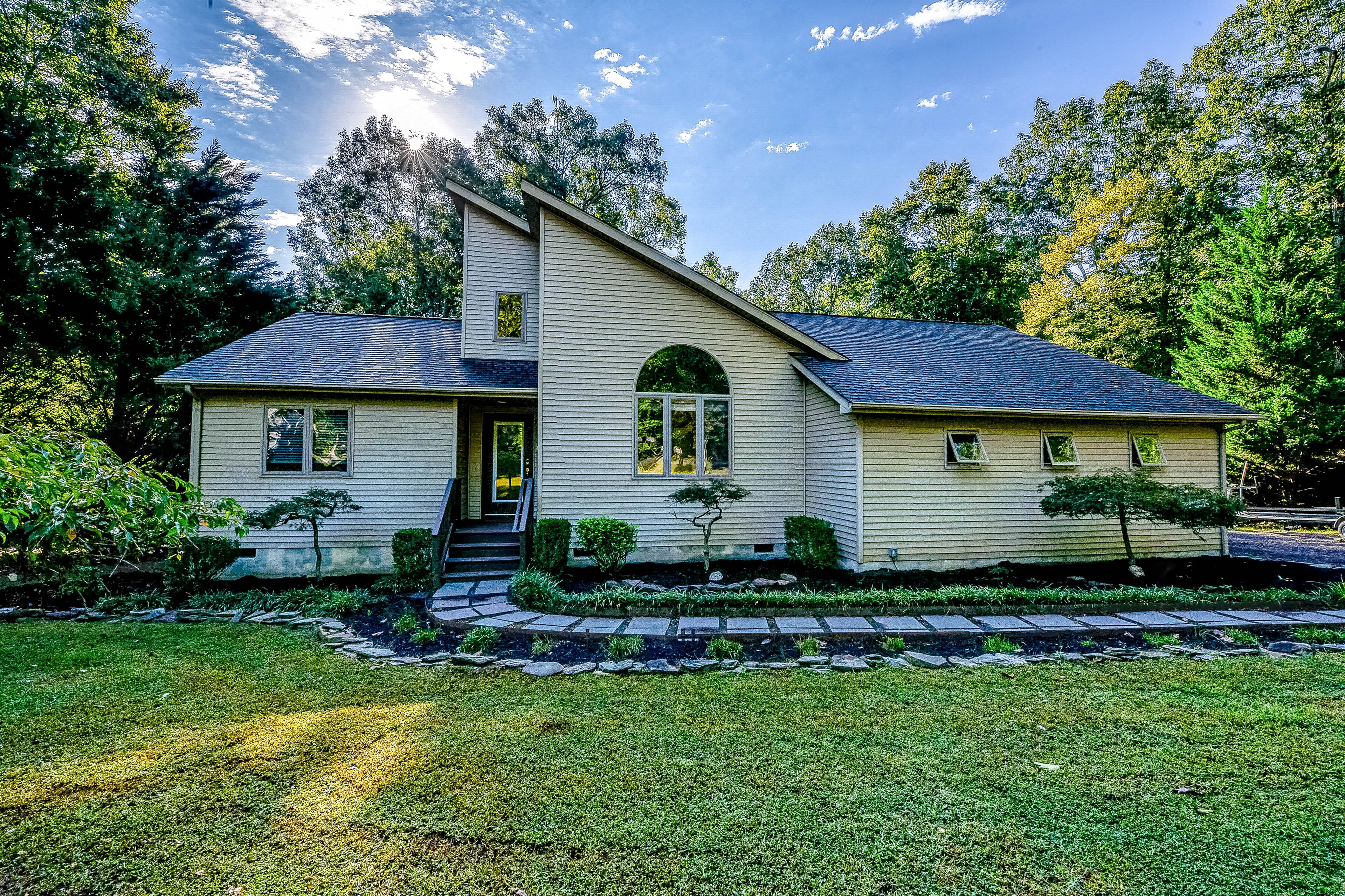A two-story house with a sloped roof, a front porch, and a well-maintained lawn.