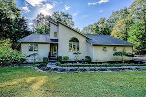 A two-story house with a sloped roof, a front porch, and a well-maintained lawn. - Dog-friendly Home With Free Wifi, Central AC, Firepit, & Furnished Deck (Mineral)