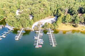 An aerial view of a marina with docks and boats, surrounded by dense forest.