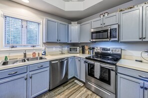 A kitchen with stainless steel appliances, a dishwasher, and light blue cabinets.