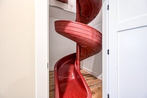 A spiral slide in a room with wooden flooring and white walls. - Dog-friendly Lakefront Home With a Game Room, Children's Items, and Firepit (Mineral)