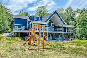 A two-story house with a large deck, a swing set, and a covered outdoor seating area. - Dog-friendly Lakefront Home With a Game Room, Children's Items, and Firepit (Mineral)