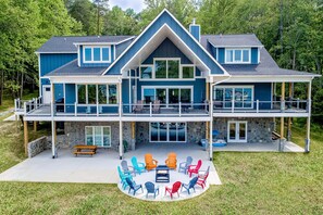 A two-story house with a balcony, outdoor seating area, and a stone foundation.