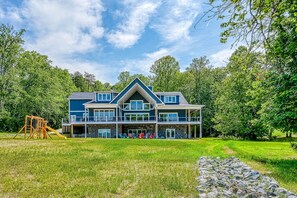 A large two-story house with a stone foundation, multiple balconies, and a covered patio area.