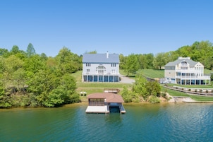 A lakeside property with a main house, a secondary house, and a docked boat.