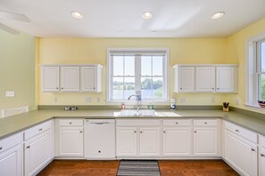 A kitchen with white cabinets, a large window, and a view of the outdoors. - Dog-friendly, Lakefront Home With Private Dock, 2 Kayaks, Decks & Game Room (Mineral)