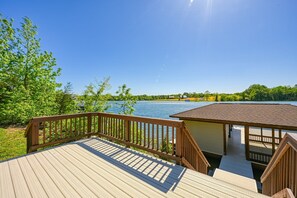 A wooden deck with a view of a lake and a small dock. - Dog-friendly, Lakefront Home With Private Dock, 2 Kayaks, Decks & Game Room (Mineral)