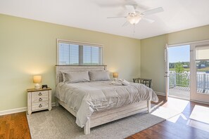 A bedroom with a bed, bedside tables, a ceiling fan, and a view of the outdoors. - Dog-friendly, Lakefront Home With Private Dock, 2 Kayaks, Decks & Game Room (Mineral)