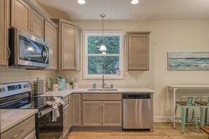 A kitchen with stainless steel appliances, wooden cabinets, a window with a view, and a painting on the wall. - Dog-friendly Lakefront Home With Dock, Game Room, Kayaks, hot Tub, & Firepit (Mineral)
