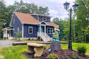A blue house with a porch, a bird sculpture, and a lamp post.