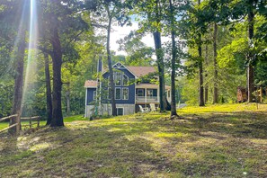 A house surrounded by trees with a deck and a wooden fence. - Dog-friendly Lakefront Home With Dock, Game Room, Kayaks, hot Tub, & Firepit (Mineral)