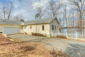 A two-story house with a garage, a front porch, and a fenced yard. - Dog-friendly, Lakefront Vacation Home w/ a Boat House, Kayaks, & Paddleboards (Mineral)