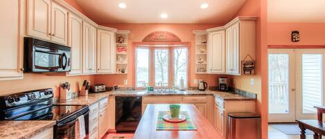 A kitchen with white cabinetry, a central island, a microwave, and a stainless steel dishwasher.