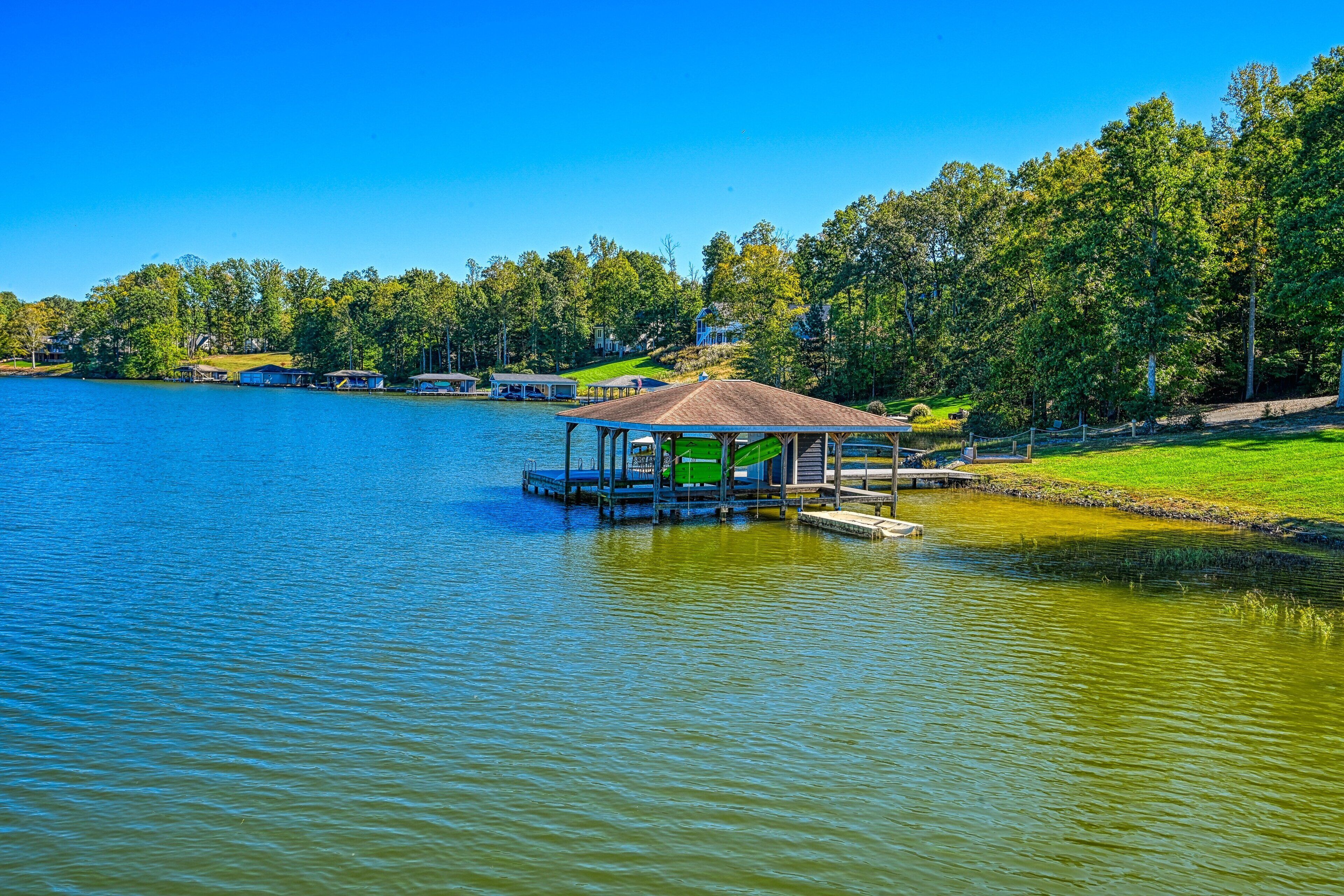 A lakeside property with a dock, a gazebo, and a house in the background.