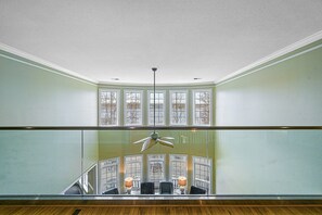 A room with a balcony, a ceiling fan, and a view of a lower level with a staircase. - Lakefront Home With Private hot Tub, Wifi, fun rec Room, & Beach Area (Mineral)