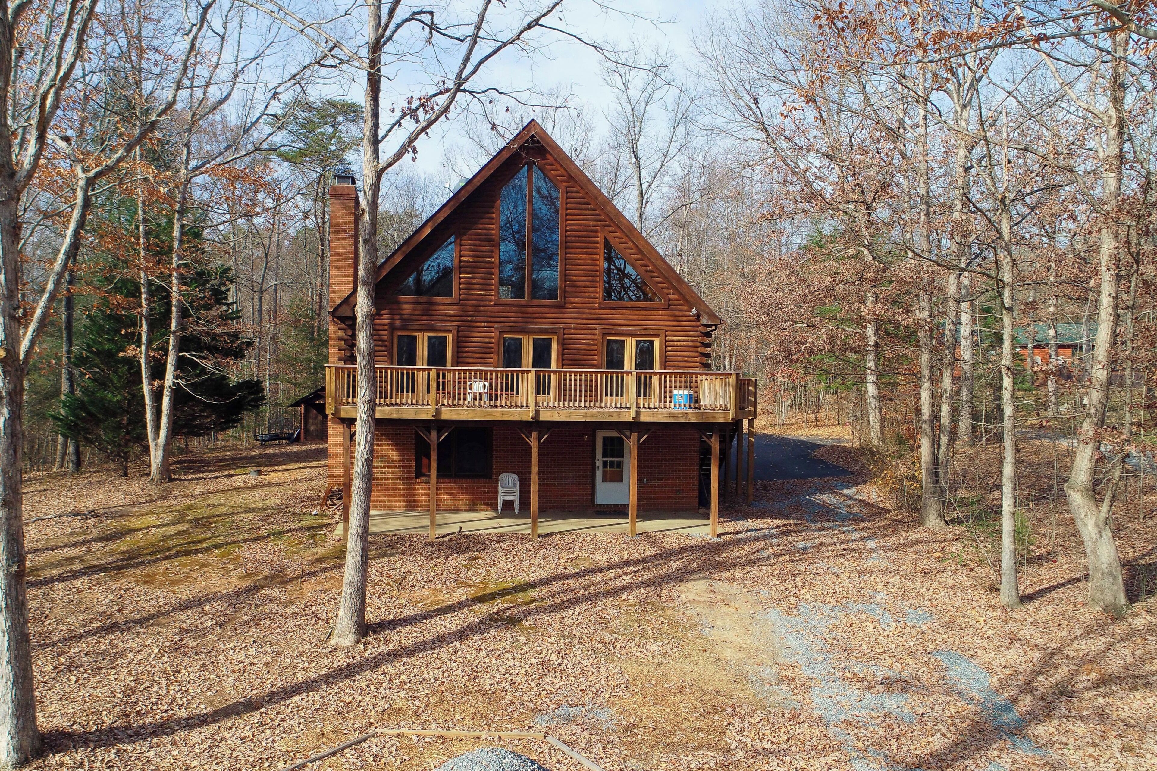 A log cabin with a balcony, surrounded by trees.