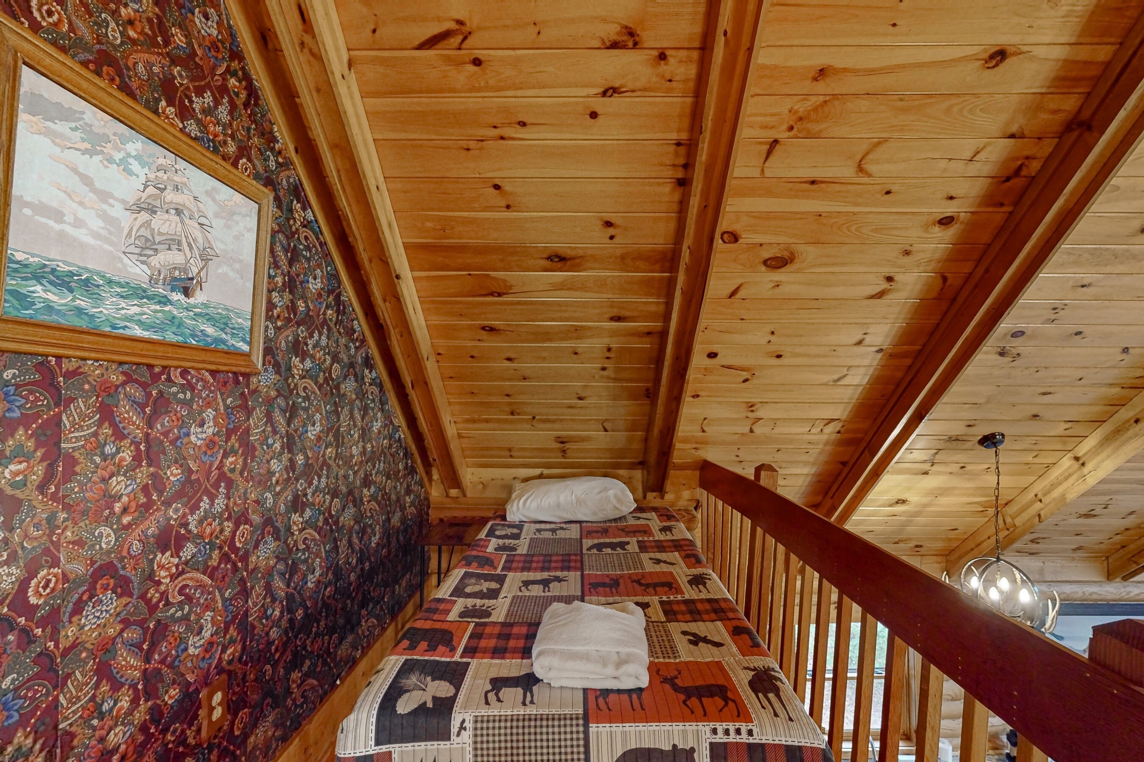 Une pièce de cabane en bois comprenant un lit, un mur décoré de motifs et un tableau encadré.