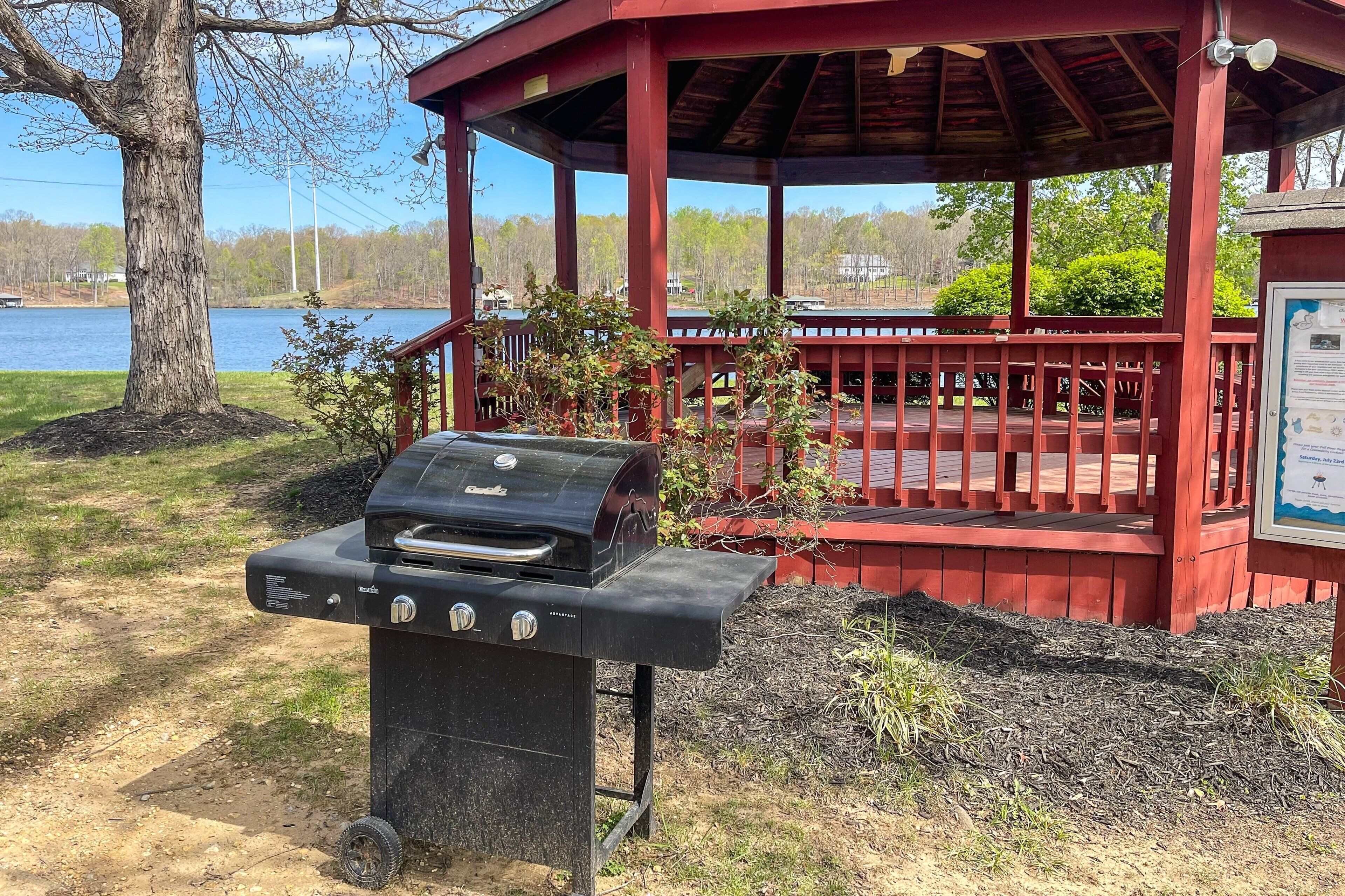 Ein Pavillon mit Grill, umgeben von einer Holzterrasse und Blick auf einen See.