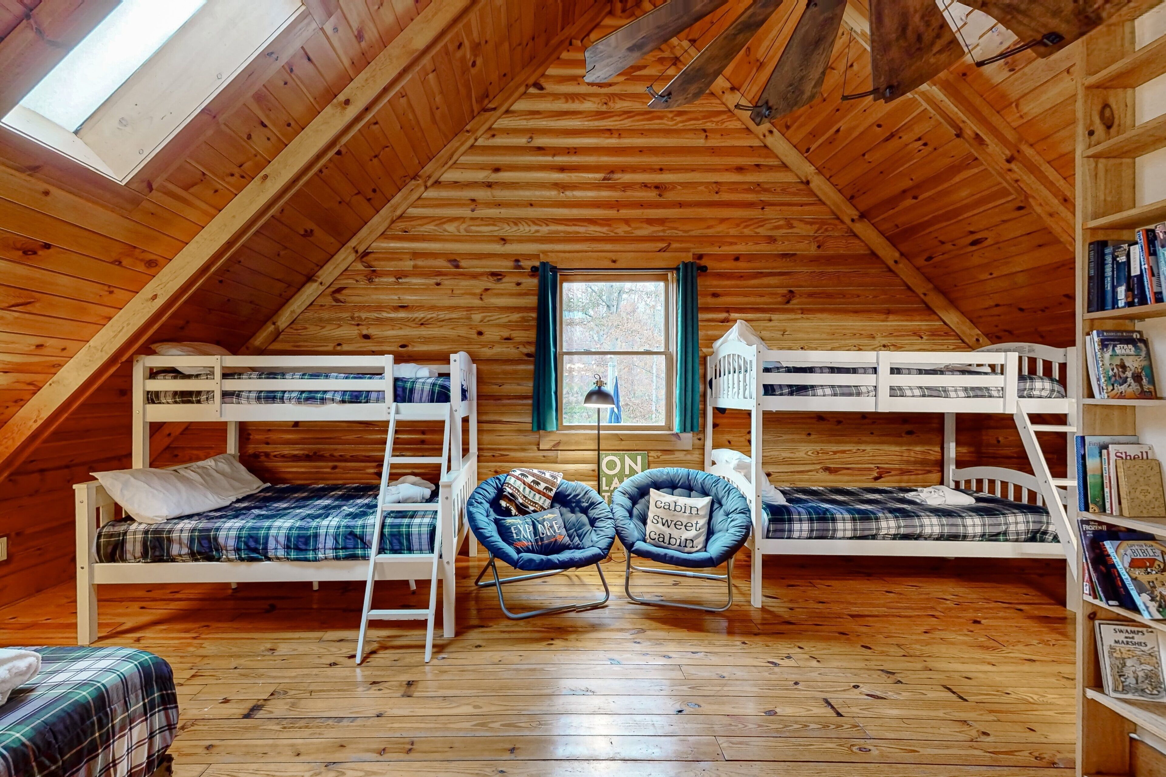 A cozy attic bedroom with bunk beds, a rocking chair, and a bookshelf.