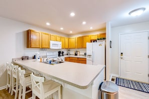A modern kitchen with wooden cabinets, a white countertop, and a stainless steel trash can. - Lakefront Home With Kayaks, Private Patio, air Hockey, Grill, & Balcony (Mineral)