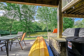 A covered patio with a table and chairs, a canoe, and a trash can. - Lakefront Home With Kayaks, Private Patio, air Hockey, Grill, & Balcony (Mineral)