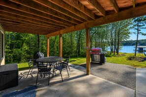 An outdoor patio with a grill, table, and chairs. - Lakeside Retreat With a Firepit, Dock, Deck, hot Tub, Pool Table - dog Friendly (Orange)