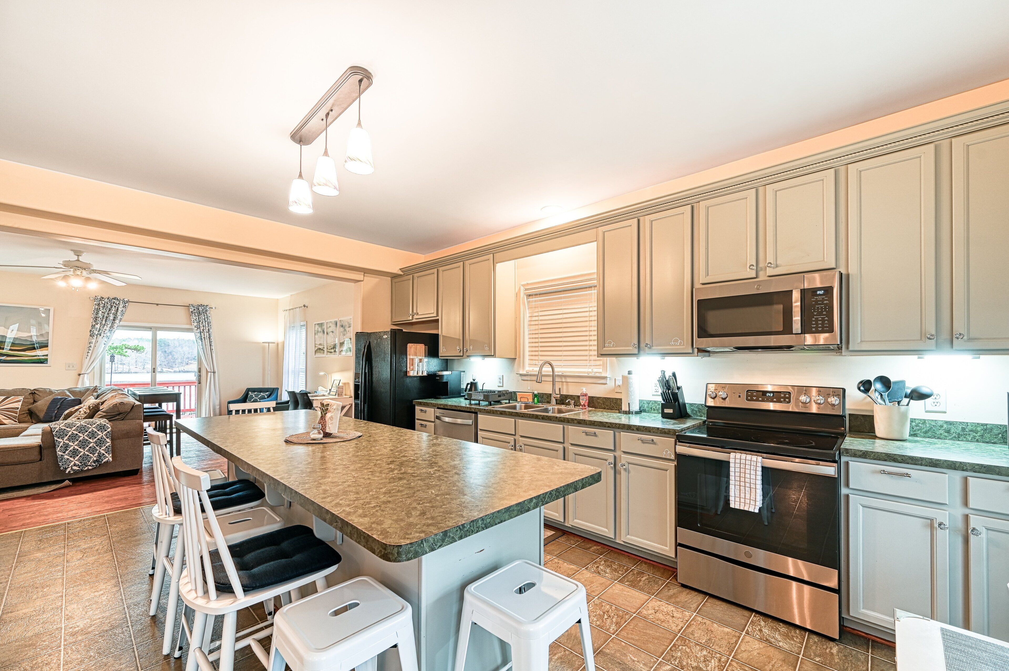 A modern kitchen with a central island, stainless steel appliances, and light-colored cabinetry.
