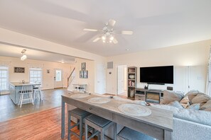A spacious living area with a dining table, bar stools, a sofa, a flat-screen TV, and a ceiling fan. - Lakeside Retreat With a Firepit, Dock, Deck, hot Tub, Pool Table - dog Friendly (Orange)