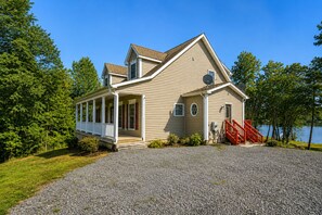 A two-story house with a covered porch, a red staircase, and a gravel driveway. - Lakeside Retreat With a Firepit, Dock, Deck, hot Tub, Pool Table - dog Friendly (Orange)