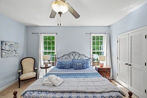 A bedroom with a bed, a chair, a ceiling fan, two windows, a door, and a painting on the wall. - Spacious Lakefront Home w/ Boat Dock, Fire pit & Pool Table - Dogs OK (Mineral)