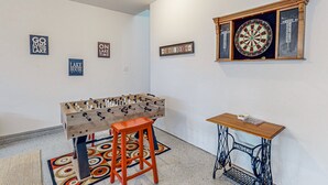 Um quarto com mesa de pebolim, dardos e mesa de costura.