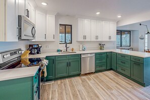 Una cucina moderna con mobili verdi, un forno in acciaio inossidabile e una lavastoviglie.