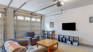 Uma garagem com televisão, mesa e sofá.