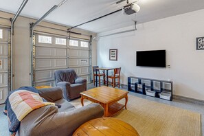 A garage with a television, a table, and a couch. - Renovated Lakehouse With Dock, hot Tub, Firepit & Bi-level Deck - Dogs OK (Mineral)