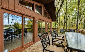 A covered outdoor deck with wooden flooring, metal chairs, and tables. - Lovely Lakefront Home With Private Brand-new Dock, Game Room, Beach, Boat Access (Mineral)