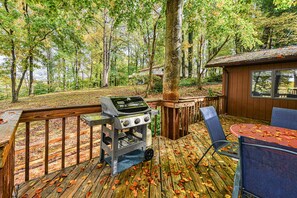 A wooden deck with a barbecue grill, outdoor seating, and a view of a forested area. - Lovely Lakefront Home With Private Brand-new Dock, Game Room, Beach, Boat Access (Mineral)