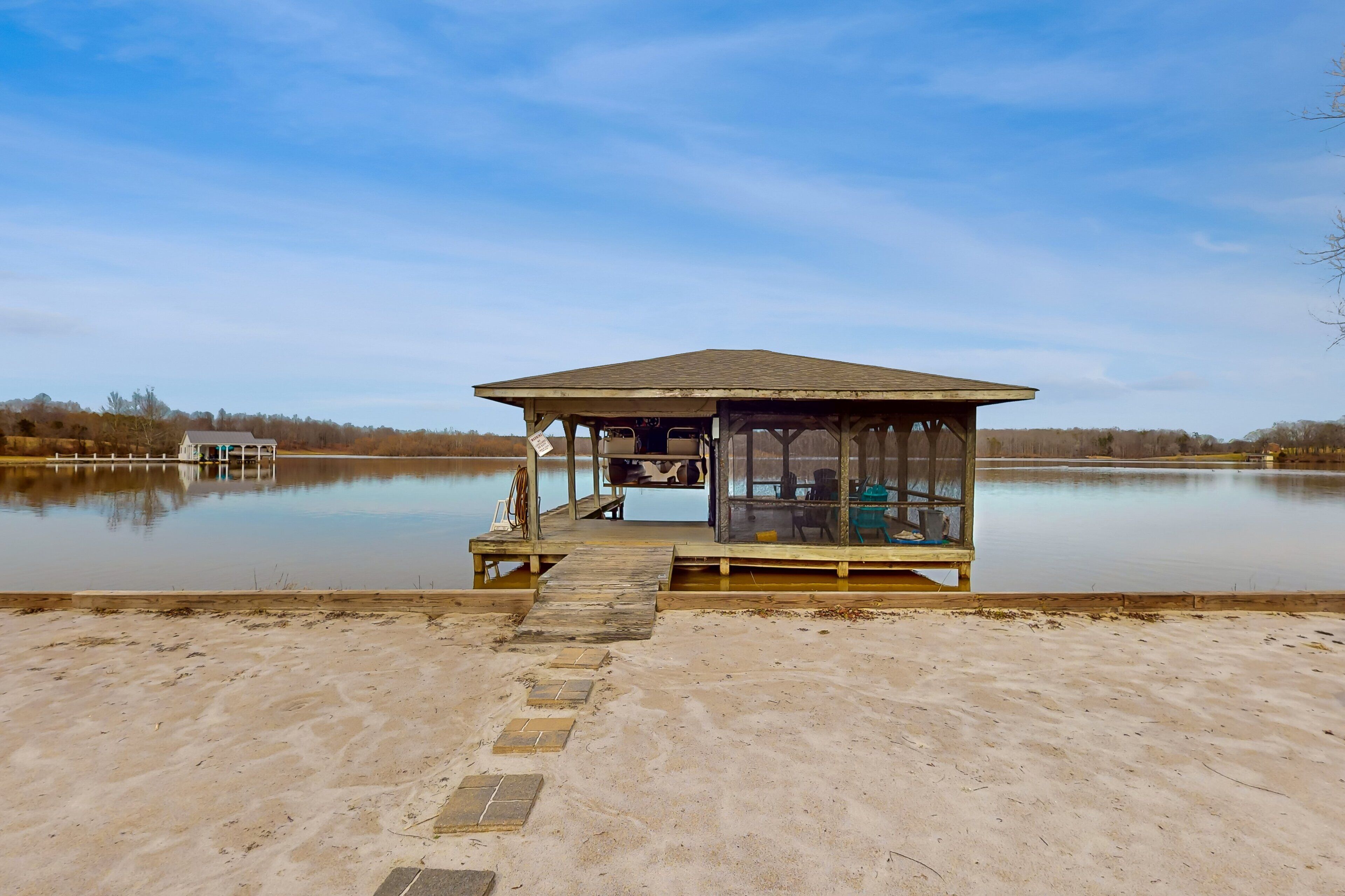 Un belvédère en bois doté d’un espace salon couvert, situé au bord d’un lac paisible.
