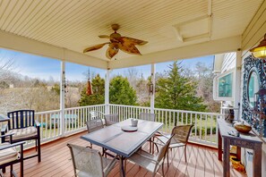 A covered outdoor area with a table and chairs, a ceiling fan, and a view of trees and a house. - Nature Lover's Lakefront Home With a Beach, Dock, Fire Ring, & More (Orange)