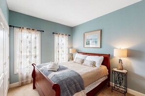 A bedroom with a bed, two bedside tables, a nightstand, a framed picture on the wall, and a window with curtains. - Nature Lover's Lakefront Home With a Beach, Dock, Fire Ring, & More (Orange)