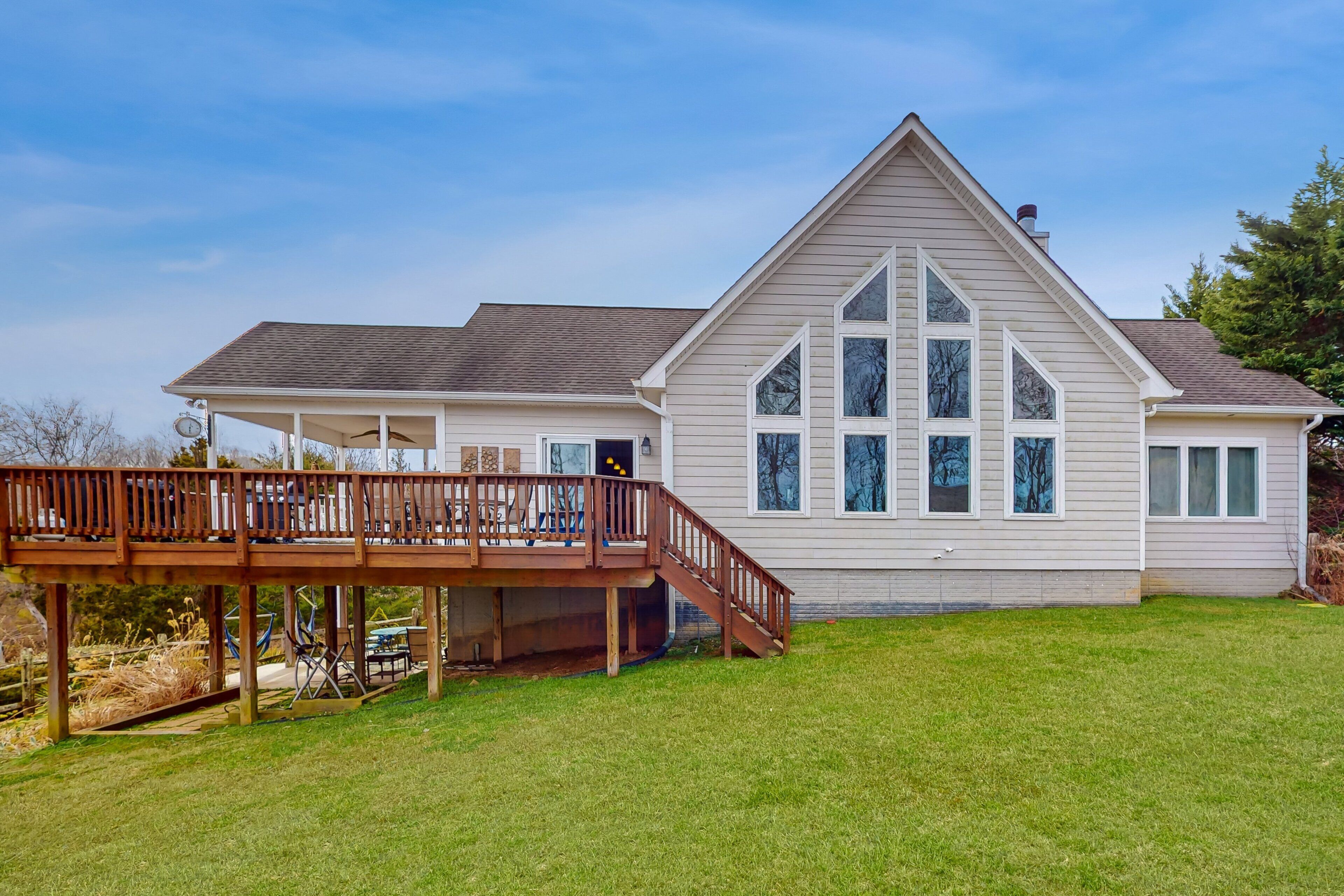A two-story house with a deck, large windows, and a sloped roof.