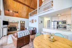A spacious living area with a fireplace, leather sofa, dining table, and kitchen with modern appliances. - Secluded Lakefront Home W/private Beach, Deck, gas Grill, Firepit, Lake Views (Bumpass)