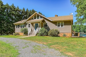 A two-story house with a front porch, a satellite dish, and a small deck. - Lakefront Adventure House With Private Dock & Wifi - Dog-friendly (Bumpass)