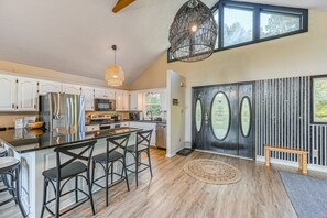 A modern kitchen with white cabinets, stainless steel appliances, and a large island with bar stools. - Lakefront Adventure House With Private Dock & Wifi - Dog-friendly (Bumpass)