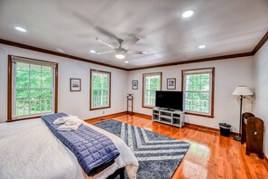 A bedroom with a bed, a ceiling fan, a TV, and large windows. - Lakefront Home in Private Location With Dock, Firepit, Game Room & Pickleball (Mineral)