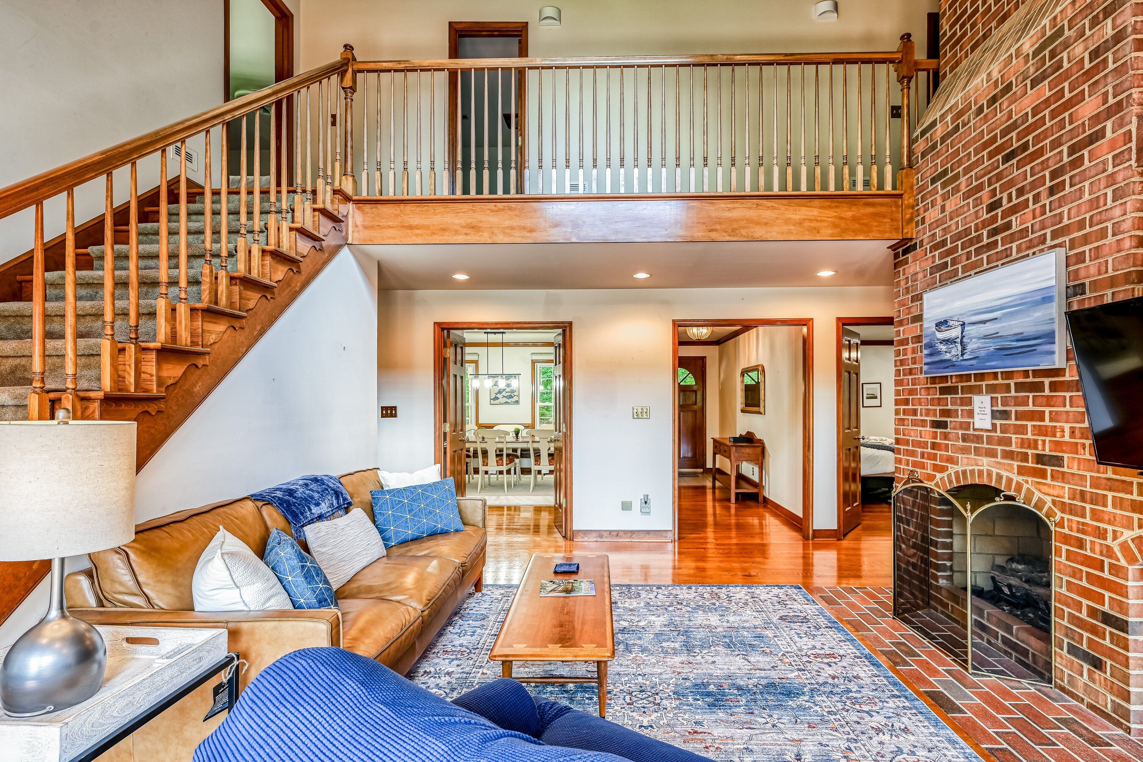 A spacious living area with a staircase, a fireplace, and a television mounted on the wall.