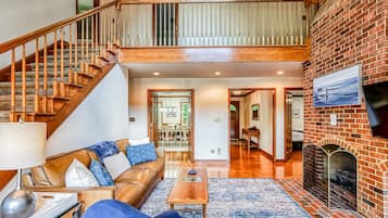 A spacious living area with a staircase, a fireplace, and a television mounted on the wall.