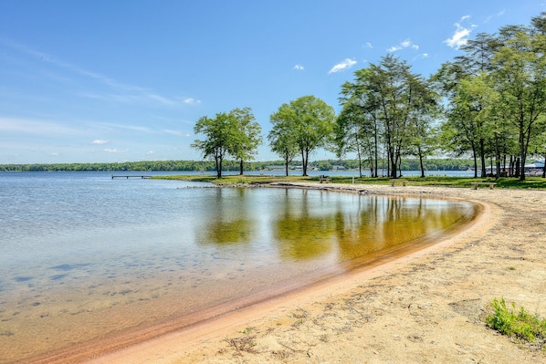 A lakeside view with clear water, sandy beach, and trees. - Three-story Lakefront Home w/ Covered Boat Slip, and Tennis/pickleball Access (Mineral)