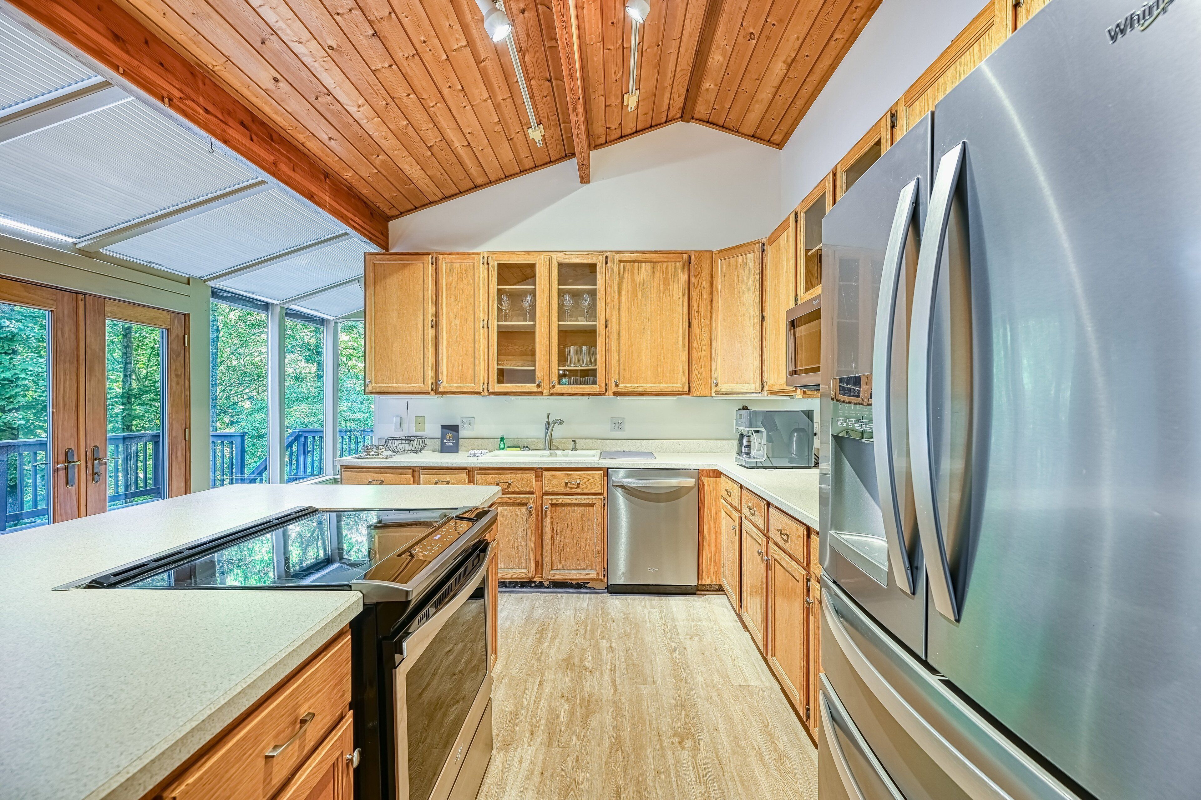 A modern kitchen with wooden cabinets, a stainless steel refrigerator, and a large island with a dishwasher.