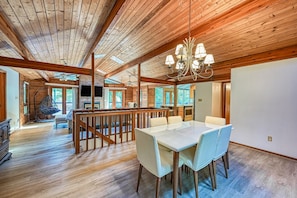 A spacious room with a wooden ceiling, a dining table with chairs, a hanging chair, and a television. - Lakefront Retreat W/private Dock, Fast Wifi, gas Grill & Central AC, Dogs (Mineral)